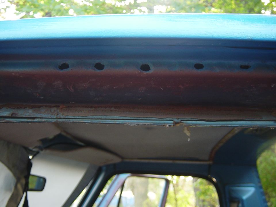 Interior view of a vehicle's roofline showing rust and holes