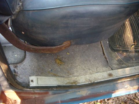 1979 Ford Bronco - The interior of a vehicle shows a rusty metal bar and worn flooring.