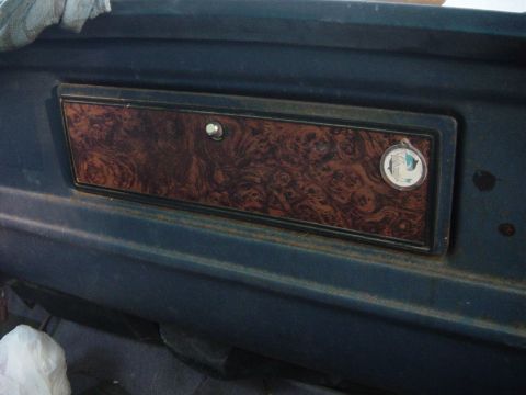 1979 Ford Bronco - Close-up of a vehicle's interior dashboard compartment with decorative woodgrain trim.