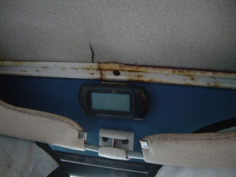 1979 Ford Bronco - The interior of a vehicle shows signs of wear, including a cracked headliner and rusty trim around a digital gauge.