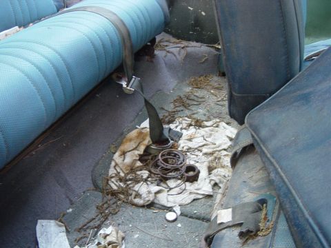 1979 Ford Bronco - The interior of a 1979 Ford Bronco shows worn blue seats and a floor littered with debris and spare parts.