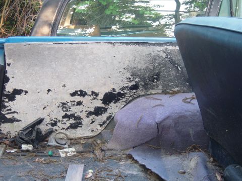 1979 Ford Bronco - The interior of a vehicle shows a worn rear panel and seat, with debris scattered on the floor.