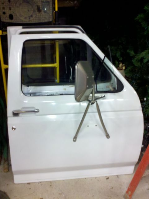 1979 Ford Bronco - A single white truck door is shown, detached from the vehicle, with a side mirror attached.