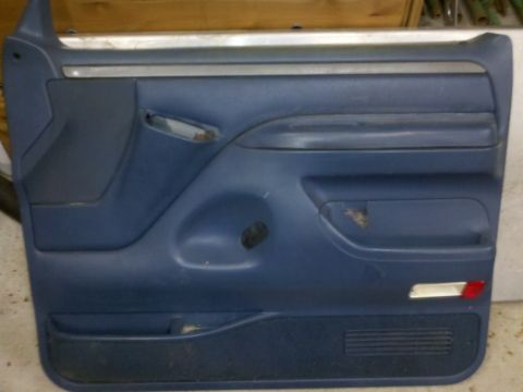 1979 Ford Bronco - This is a blue interior door panel, likely from a Ford truck or SUV, a speaker grille and chrome trim.