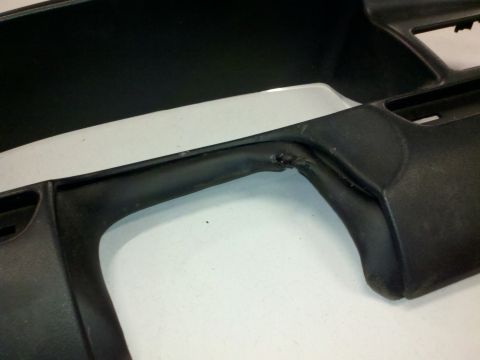 1979 Ford Bronco - Close-up of a damaged black plastic dashboard trim piece with a silver accent.