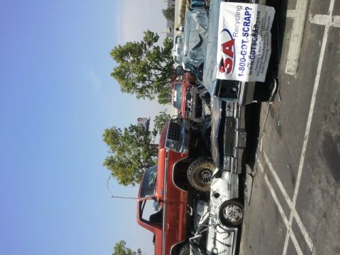 1978 Ford Bronco - Multiple vehicles are stacked and crushed together at a recycling facility.