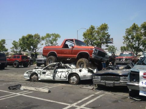 1978 Ford Bronco - Orange 1978 Ford Bronco is piled on top of other wrecked vehicles in a junkyard.