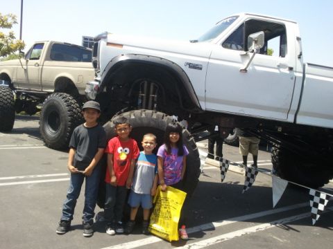 1978 Ford Bronco - Children pose with a heavily modified pickup truck, with another similar vehicle in the background.