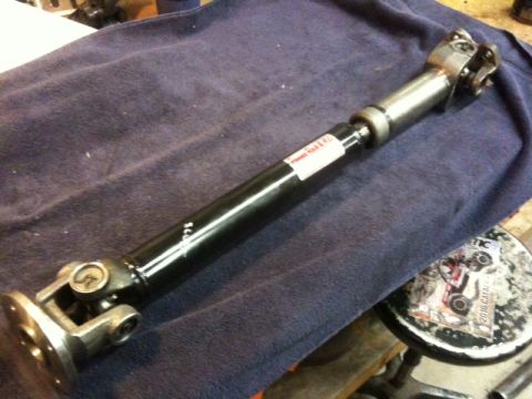 1987 Suzuki Samurai - Driveshaft with U-joints and a white label is laid out on a blue cloth.