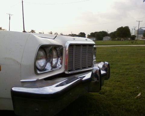 1976 Ford Torino - Close-up of the front grille and headlights of a white 1976 Ford Torino parked on grass.