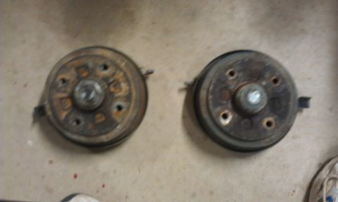 1991 Ford Festiva - A pair of old, rusty brake drums are shown resting on a floor.