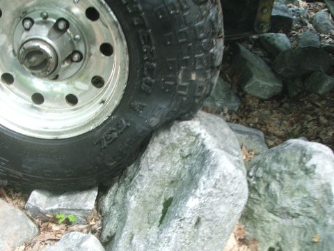 1996 Ford Bronco - A vehicle's tire is positioned on large rocks, suggesting off-road use.