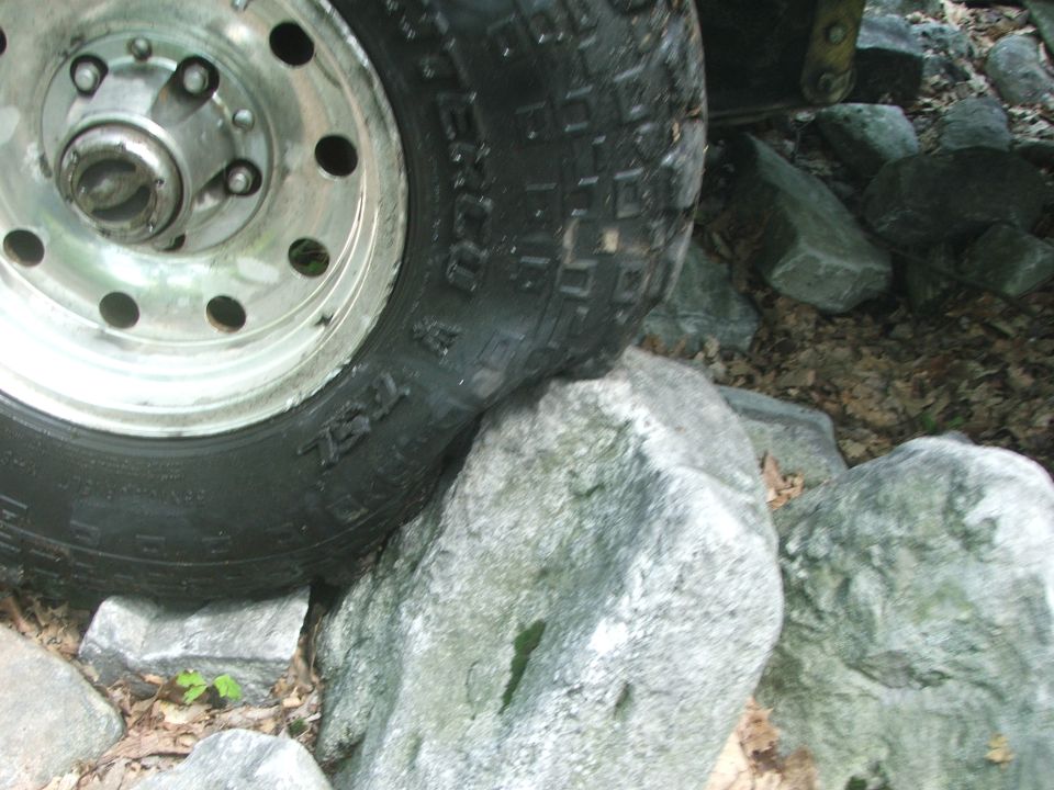Tire with visible text 'TRAIL' on a rock, part of a vehicle off-roading