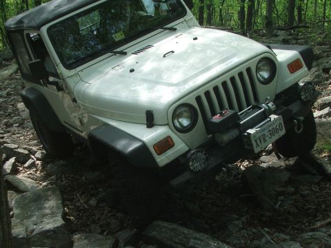 1996 Ford Bronco - Jeep Wrangler TJ tackling a challenging off-road course with steep inclines and large rocks.