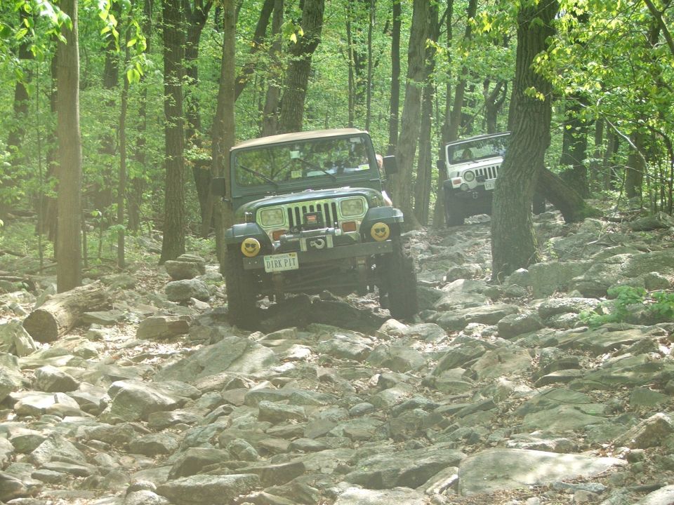 Green Jeep Wrangler on rocky trail with another Jeep behind it