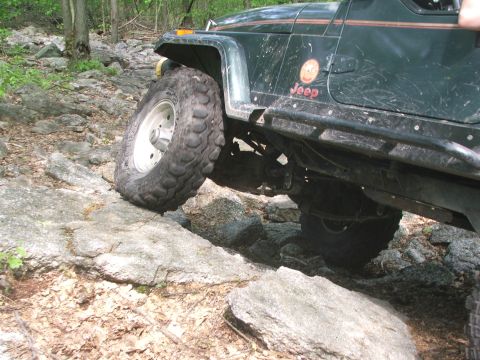 1996 Ford Bronco - A green Jeep Wrangler tackles a challenging rocky trail, its off-road capabilities.