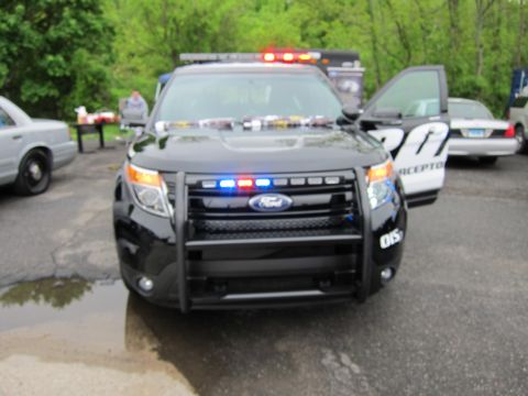 1991 Ford LTD Crown Victoria - Front view of a black Ford Police Interceptor utility SUV with a push bar and activated emergency lights in a lot.