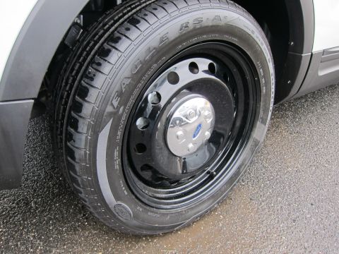 1991 Ford LTD Crown Victoria - Close-up of a black steel wheel with a Ford center cap and Goodyear Eagle RS-A tire on wet pavement.