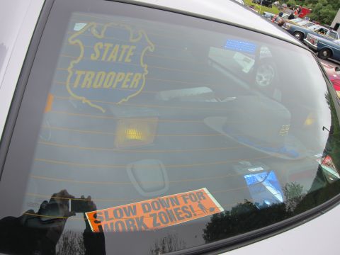 1991 Ford LTD Crown Victoria - car's rear window showing a gold STATE TROOPER shield decal and an orange SLOW DOWN FOR WORK ZONES sticker.