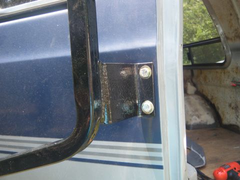 1981 Ford E350 - Detail of a door hinge on a blue van, showing its mounting hardware.