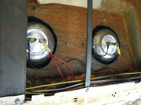 1981 Ford E350 - Close-up view of two round headlights and their electrical connections within a vehicle's housing.