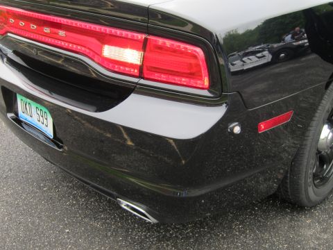 1991 Ford LTD Crown Victoria - Close-up of a black Dodge sedan's rear bumper and taillight, showing a green license plate reading DKD 599.