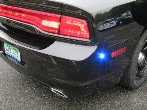 1991 Ford LTD Crown Victoria - rear quarter of a black Dodge sedan with a Dodge taillight, green DKD 599 plate and a glowing blue strobe light.