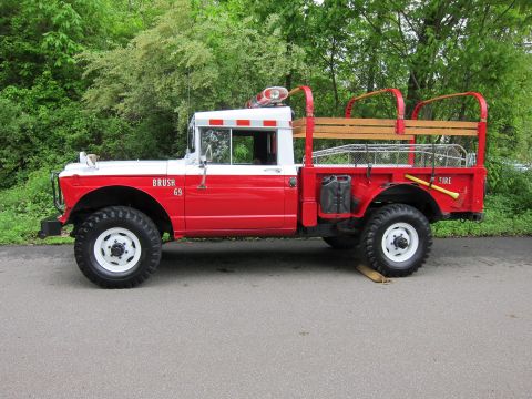 1991 Ford LTD Crown Victoria - Side view of a vintage red-and-white 4x4 military-style fire brush truck lettered Brush 69 with wooden stake bed rails.