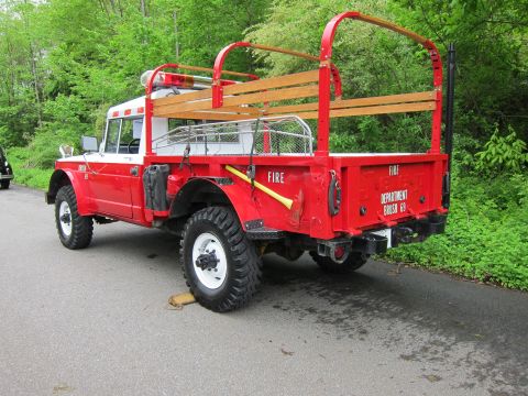 1991 Ford LTD Crown Victoria - Rear three-quarter view of a red 4x4 fire brush truck with wooden stake-bed rails lettered Fire Department Brush 69.