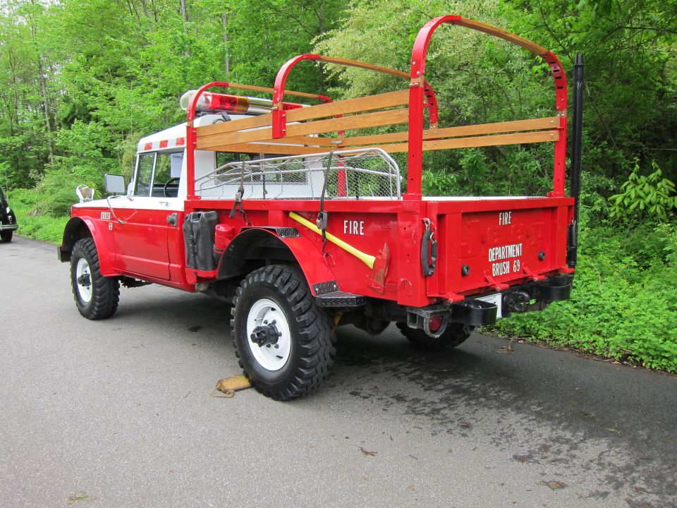 Rear three-quarter of a red 4x4 fire brush truck with wooden stake bed