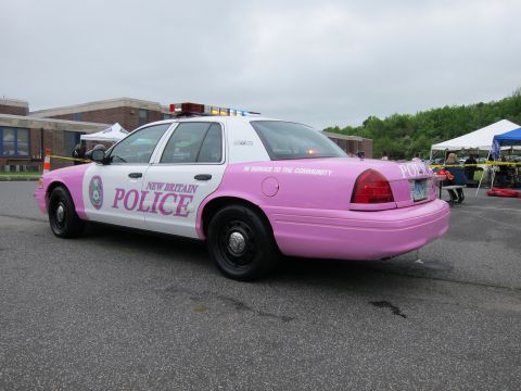 1991 Ford LTD Crown Victoria - pink-and-white Ford Crown Victoria lettered New Britain Police with a light bar, viewed from the rear three-quarter angle.