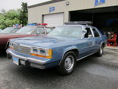1991 Ford LTD Crown Victoria - blue Ford LTD Crown Victoria police cruiser with a roof light bar sits in front of an open garage bay.