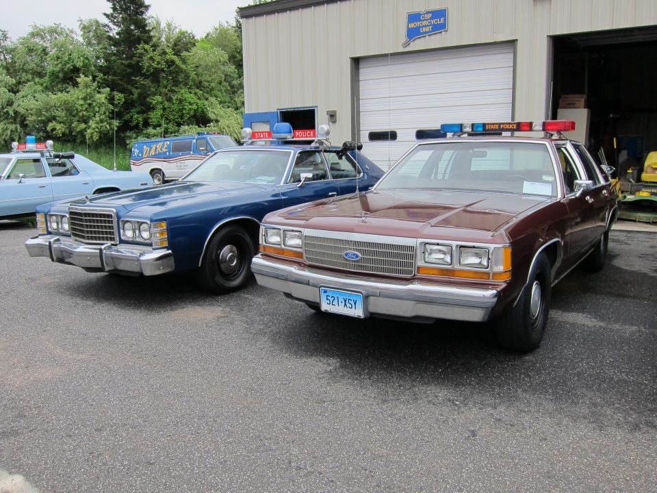 Maroon Ford LTD Crown Victoria and blue sedan police cars with light bars