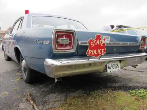 1991 Ford LTD Crown Victoria - Rear of a blue Ford Custom 500 sedan bearing a red STATE POLICE shield decal on the trunk and a roof beacon.