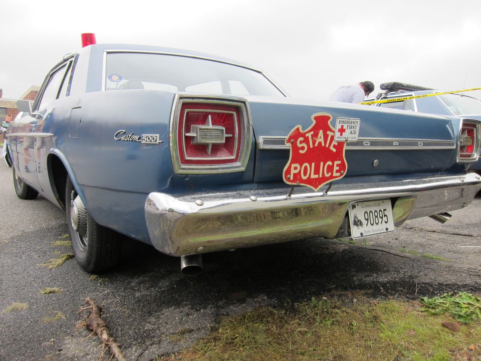 Rear of blue Ford Custom 500 with red STATE POLICE shield decal on trunk
