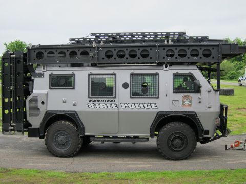 1991 Ford LTD Crown Victoria - Side view of a gray Connecticut State Police armored 4x4 tactical truck with a heavy roof rack and barred windows.