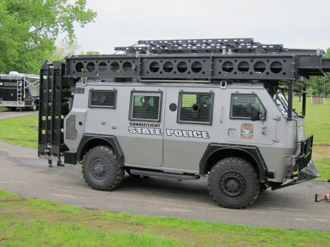 1991 Ford LTD Crown Victoria - Side profile of a gray Connecticut State Police armored 4x4 tactical truck parked beside a grassy field.