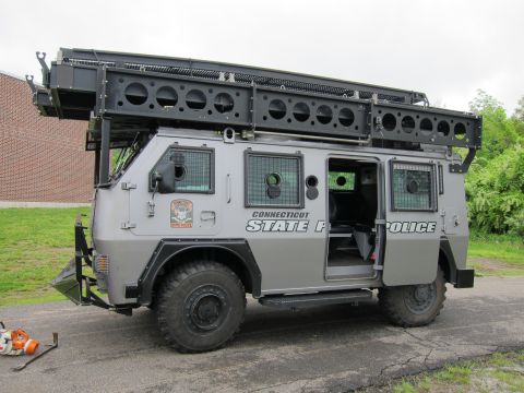 1991 Ford LTD Crown Victoria - Side view of a gray Connecticut State Police armored tactical truck with a side door open, parked by a brick building.