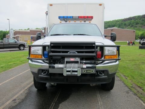 1991 Ford LTD Crown Victoria - Head-on front view of a white Ford emergency box truck fitted with a brush guard, winch, and roof light bar.