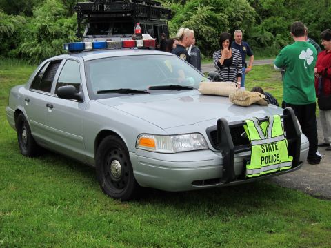 1991 Ford LTD Crown Victoria - silver Ford Crown Victoria State Police sedan with roof-mounted equipment and a STATE POLICE banner, surrounded by onlookers.