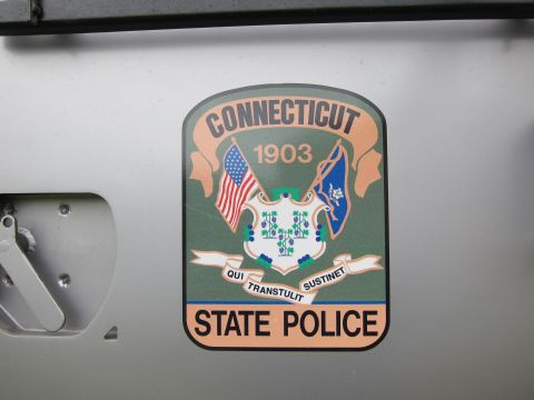 1991 Ford LTD Crown Victoria - Close-up of a Connecticut State Police 1903 shield decal with flags and Qui Transtulit Sustinet motto on a gray panel.
