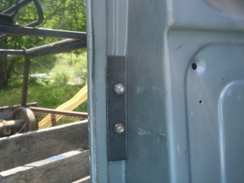 1981 Ford E350 - A close-up view of a metal bracket with two bolts attached to the door of a vehicle.