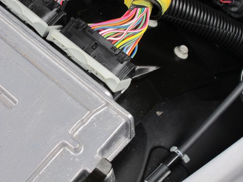 1991 Ford LTD Crown Victoria - Close-up of an automotive control module and its multicolored wiring harness connectors in an engine bay.