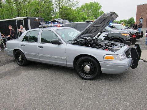 1991 Ford LTD Crown Victoria - silver Ford Crown Victoria police sedan with black steel wheels parked at an outdoor show, other patrol cars behind it.