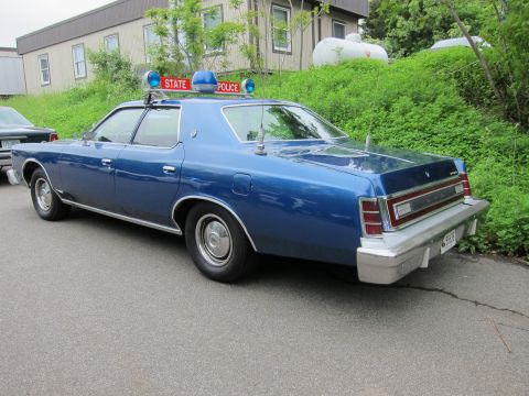 1991 Ford LTD Crown Victoria - Rear three-quarter view of a blue Ford LTD sedan with a STATE POLICE roof sign and blue beacon.