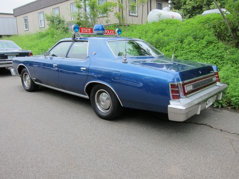 1991 Ford LTD Crown Victoria - Rear three-quarter view of a blue Ford LTD sedan displaying a red STATE POLICE roof sign and blue beacon.