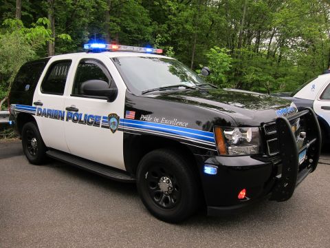 1991 Ford LTD Crown Victoria - black-and-white Chevrolet Tahoe lettered DARIEN POLICE with blue stripe, roof lightbar, and front pushbar.