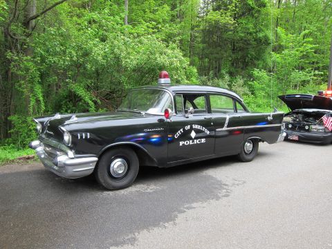 1991 Ford LTD Crown Victoria - black 1957 Chevrolet sedan lettered CITY OF SHELTON POLICE with chrome trim and a red roof beacon.