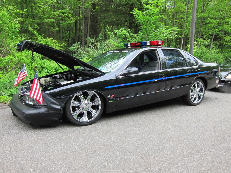 Black Chevrolet Impala SS police-style car with hood up and chrome wheels