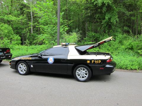 1991 Ford LTD Crown Victoria - Rear three-quarter view of a black-and-white Chevrolet Camaro marked State Trooper and FHP with roof light bar.